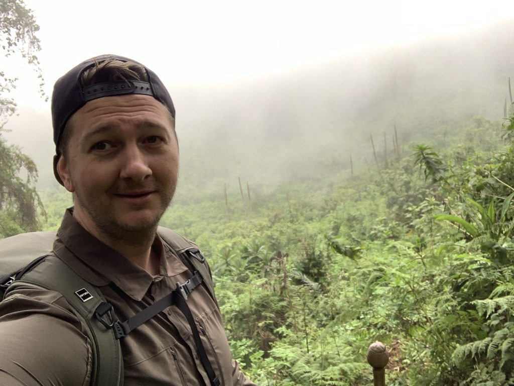 Portrait in the rainforest in Borneo, backpack on, mist over the canopy behind