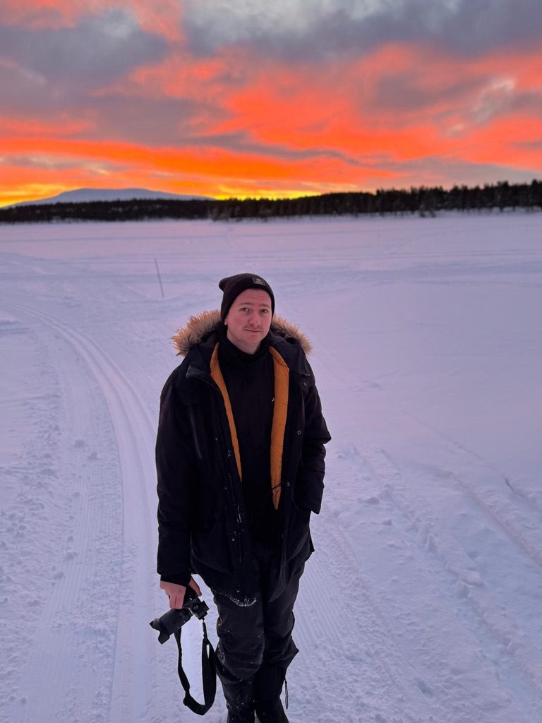 Portrait in Lapland at sunset, camera in hand, snow underfoot