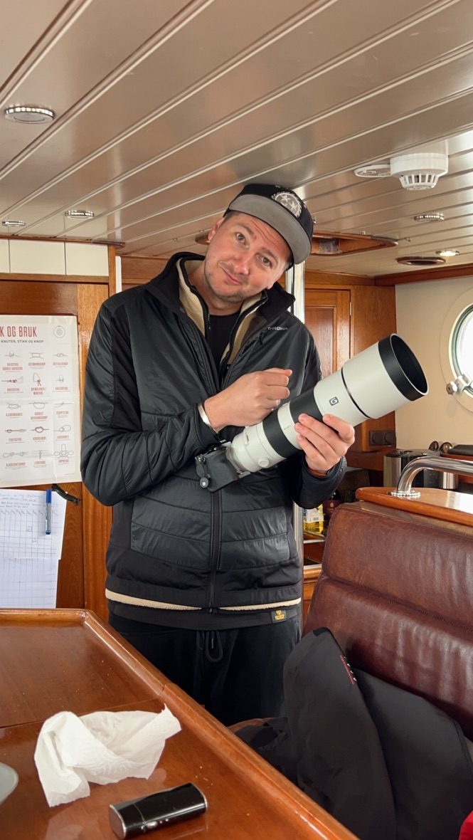 Portrait aboard a boat in Svalbard, holding a telephoto lens