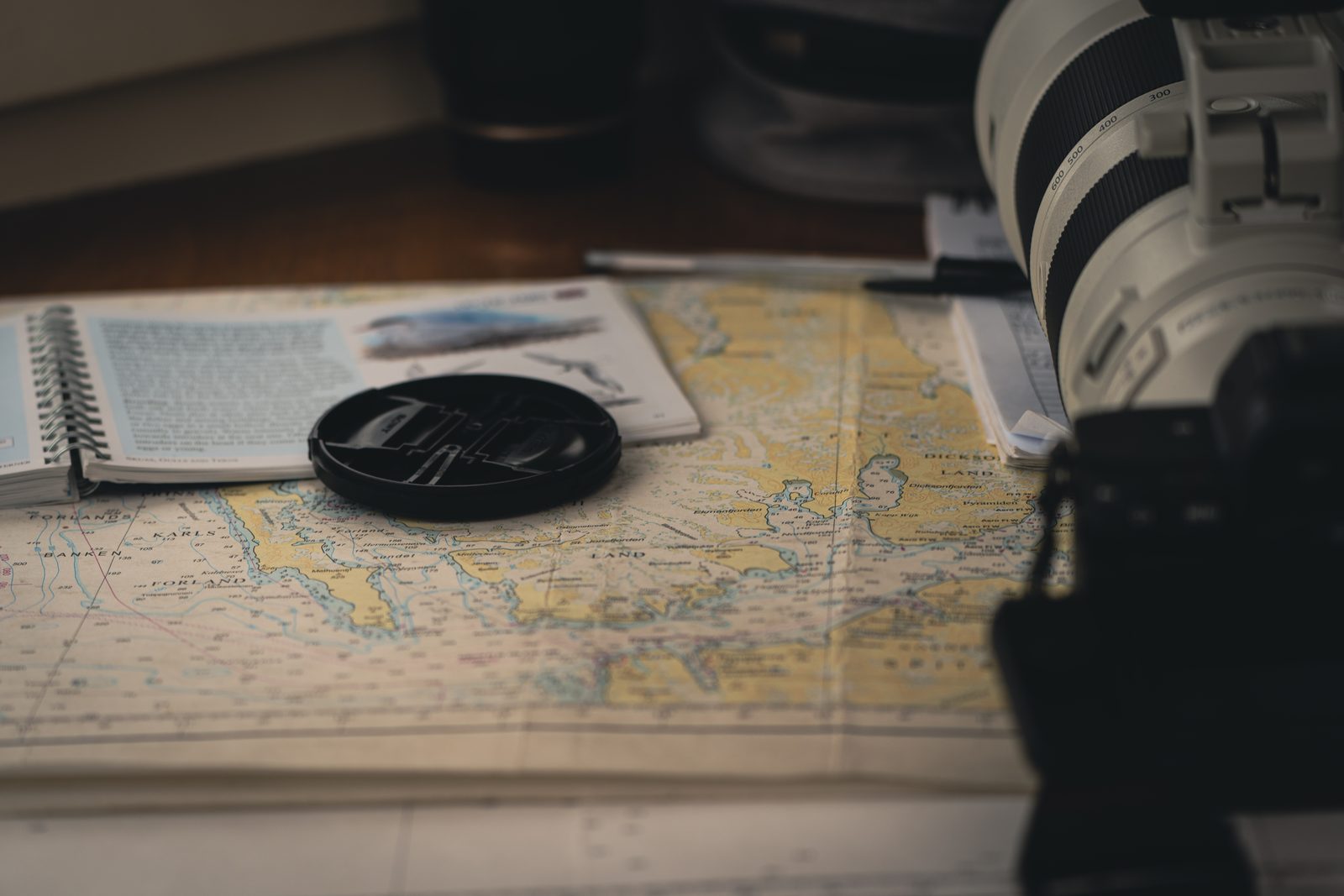 Nautical charts and camera gear on a table before a landing